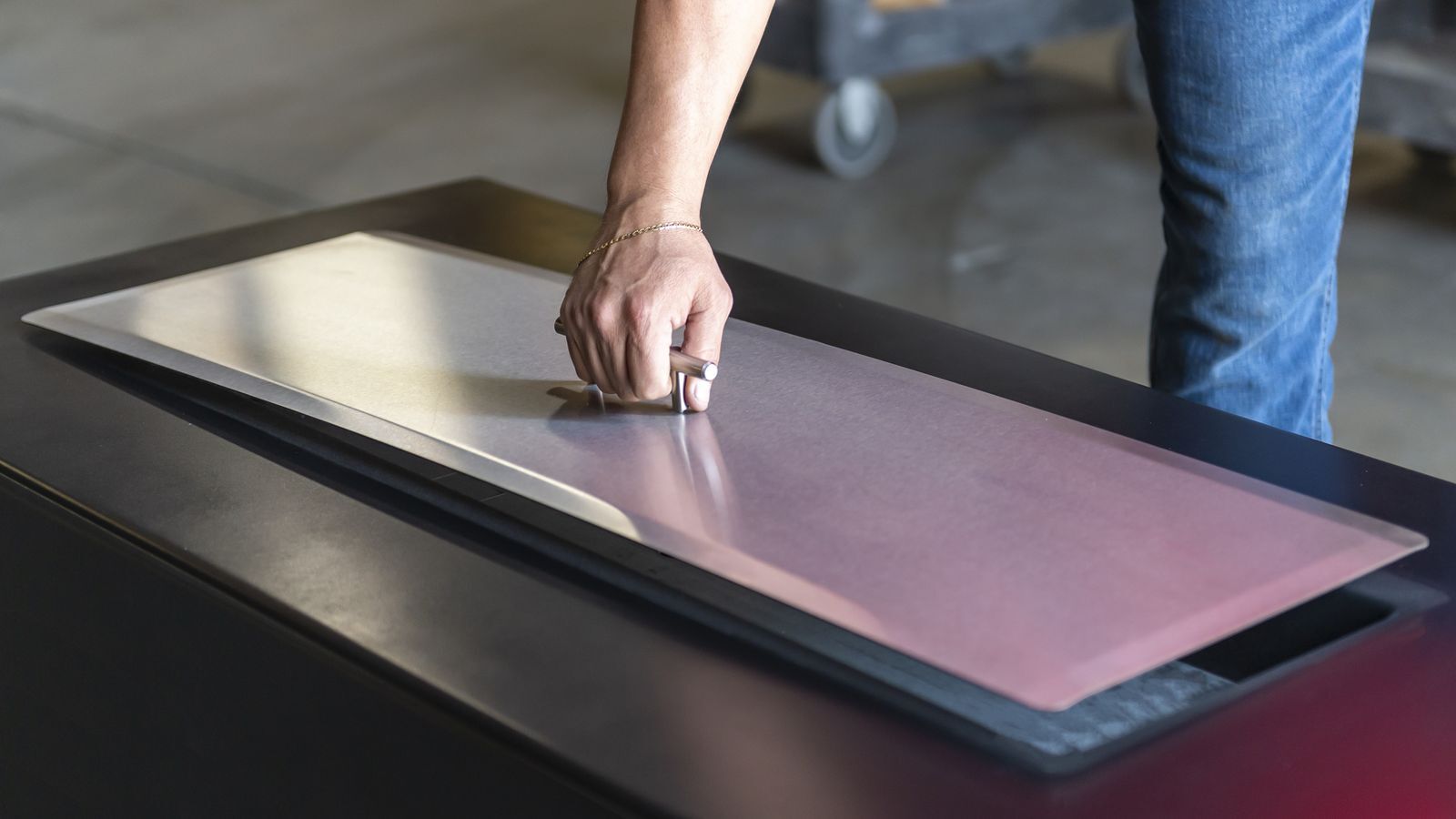 Hand lifting a custom stainless steel fire pit lid off a linear fire table A close-up look at how easily a well-fitted stainless steel lid lifts on and off, keeping the burner protected between uses.